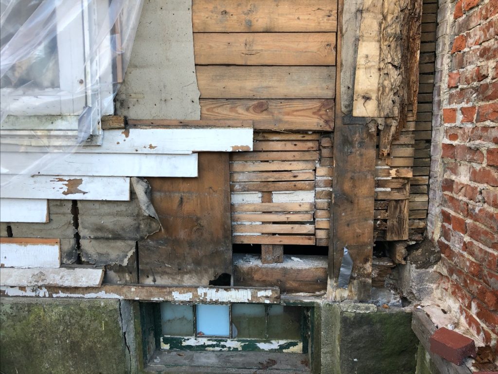 A close-up of the layers of wood revealed after removing vinyl siding from an old house.