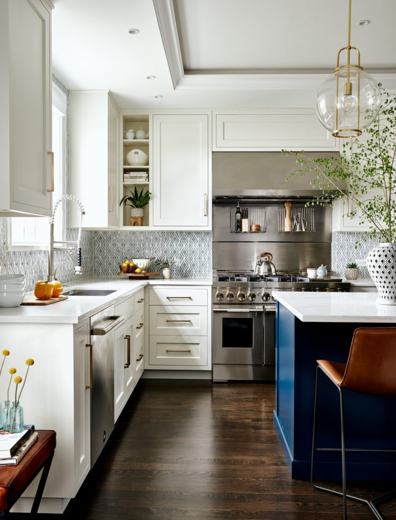 Modern kitchen design: cream colored cabinets, an island with dark blue detail, and a Viking range.